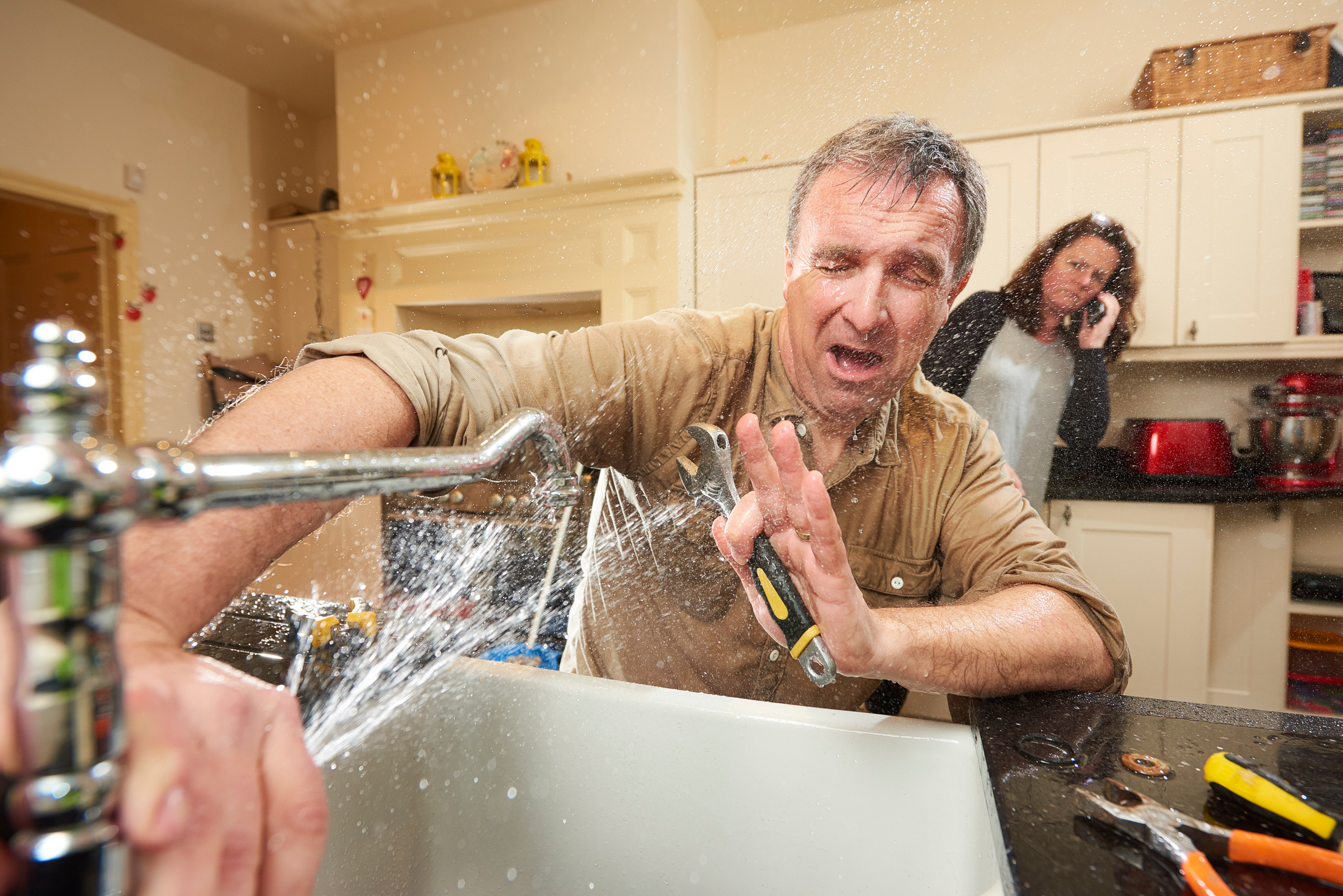 Man being sprayed in the face with water from leaking faucet to illustrate plumbing services in Perkasie, PA from Resistance Plumbing. 